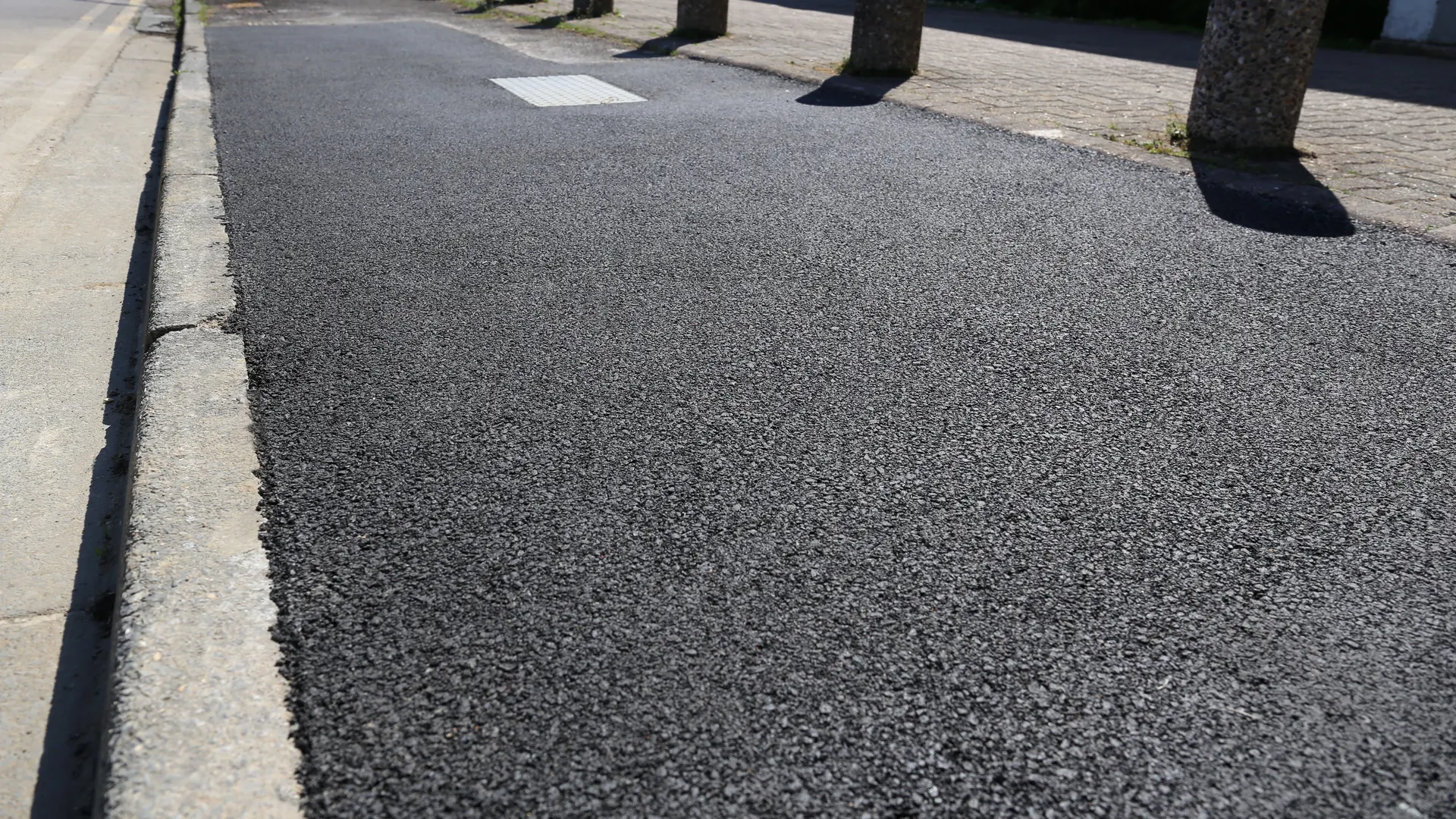 Freshly resurfaced footway beside a row of concrete bollards